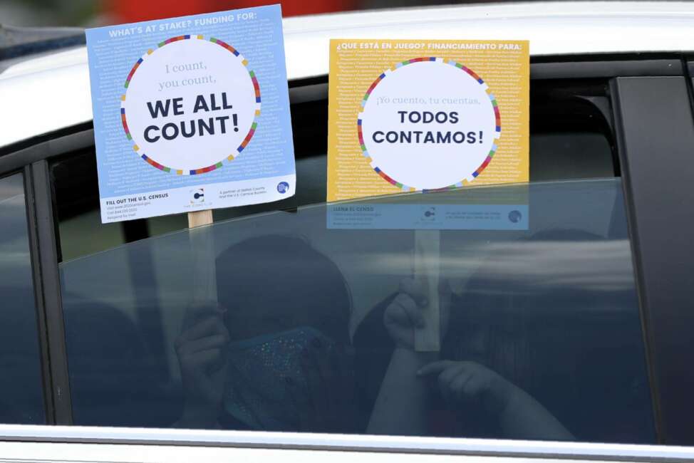 FILE - In this June 25, 2020, file photo, two young children hold signs through the car window that make reference to the 2020 U.S. Census as they wait in the car with their family at an outreach event in Dallas. Thousands of census takers are about to begin the most labor-intensive part of America’s once-a-decade headcount (AP Photo/Tony Gutierrez, File)