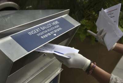 FILE - In this July 7, 2020, file photo a woman wearing gloves drops off a mail-in ballot at a drop box in Hackensack, N.J. After months of hearing President Donald Trump denigrate mail-in balloting, Republicans in the critical battleground state now find themselves far behind Democrats in the perennial push to urge their voters to vote remotely. While Democrats have doubled the number of their voters who've asked for a mail ballot compared to 2016, Republicans have only increased by about 20% since the same time. (AP Photo/Seth Wenig, File)