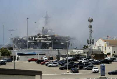 A helicopter drops water on the USS Bonhomme Richard as crews fight the fire Monday, July 13, 2020, in San Diego. Fire crews continue to battle the blaze Monday after 21 people suffered minor injuries in an explosion and fire Sunday on board the USS Bonhomme Richard at Naval Base San Diego. (AP Photo/Gregory Bull)