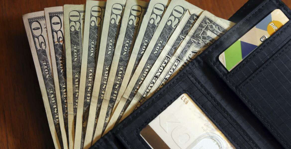 FILE - In this June 15, 2018, file photo, cash is fanned out from a wallet in North Andover, Mass.  High-interest payday and online lenders have long been among the few options for Americans with bad credit and lower incomes. Guidance issued in the spring by federal regulators cut a previously suggested rate cap on loans and that could mean banks start lending small-dollar, high-interest loans. (AP Photo/Elise Amendola, File)