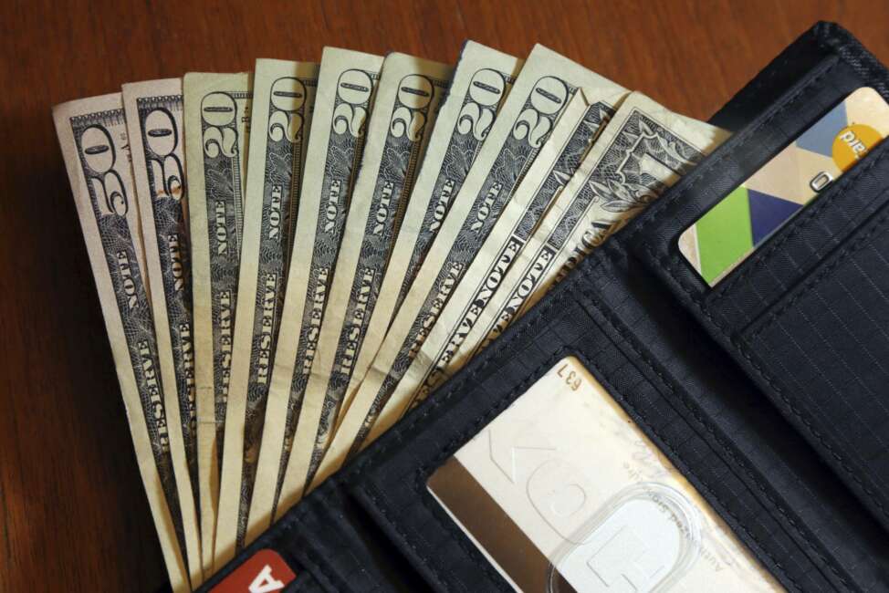 FILE - In this June 15, 2018, file photo, cash is fanned out from a wallet in North Andover, Mass.  High-interest payday and online lenders have long been among the few options for Americans with bad credit and lower incomes. Guidance issued in the spring by federal regulators cut a previously suggested rate cap on loans and that could mean banks start lending small-dollar, high-interest loans. (AP Photo/Elise Amendola, File)