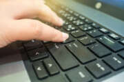 close up female's finger pushing enter button on laptop keyboard.