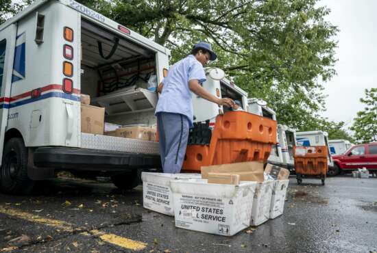 Letter carriers load mail trucks for deliveries at a U.S. Postal Service facility in McLean, Va., Friday, July 31, 2020. Delays caused by an increase in voting by mail may contribute to public doubts about the results. The public might not know the winner of the presidential race on Election Day because of a massive shift to voting by mail during the coronavirus pandemic. That’s because mail ballots take longer to count because of security procedures and laws in some states that limit when they can be processed.  (AP Photo/J. Scott Applewhite)