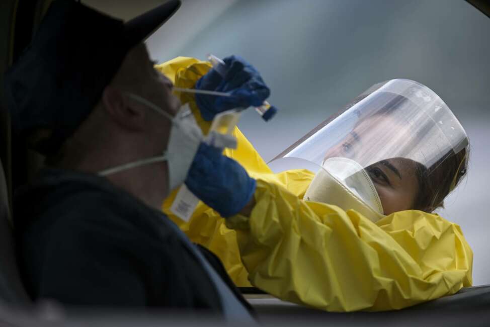 FILE - In this May 23, 2020, file photo Elizabeth Santoro, a medic with the Minnesota Air National Guard 133rd Medical Group, administers a free COVID-19 test at the Minneapolis Armory in Minneapolis. Since the pandemic began, Congress has set aside trillions of dollars to ease the crisis. A joint KHN and Associated Press investigation finds that many communities with big outbreaks have spent little of that federal money on local public health departments for work such as testing and contact tracing. Others, like Minnesota, were slow to do so. (Aaron Lavinsky/Star Tribune via AP, File)