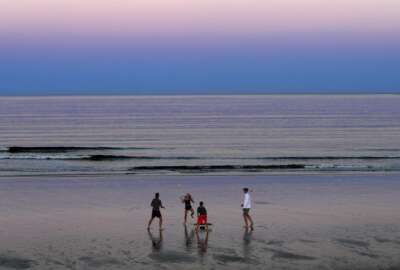 A group of people play Spikeball at twilight on the beach, Thursday, Aug. 7, 2020, in Ocean Park, Maine. As the summer tourist season reaches its peak Maine's coronavirus positivity rate remains among the lowest in the nation. (AP Photo/Robert F. Bukaty)