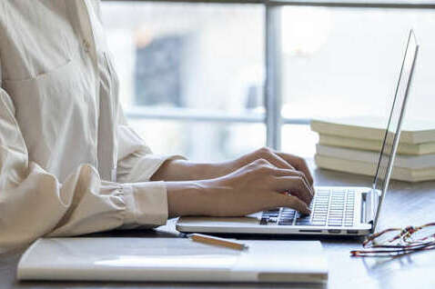 The hand of a young woman working remotely