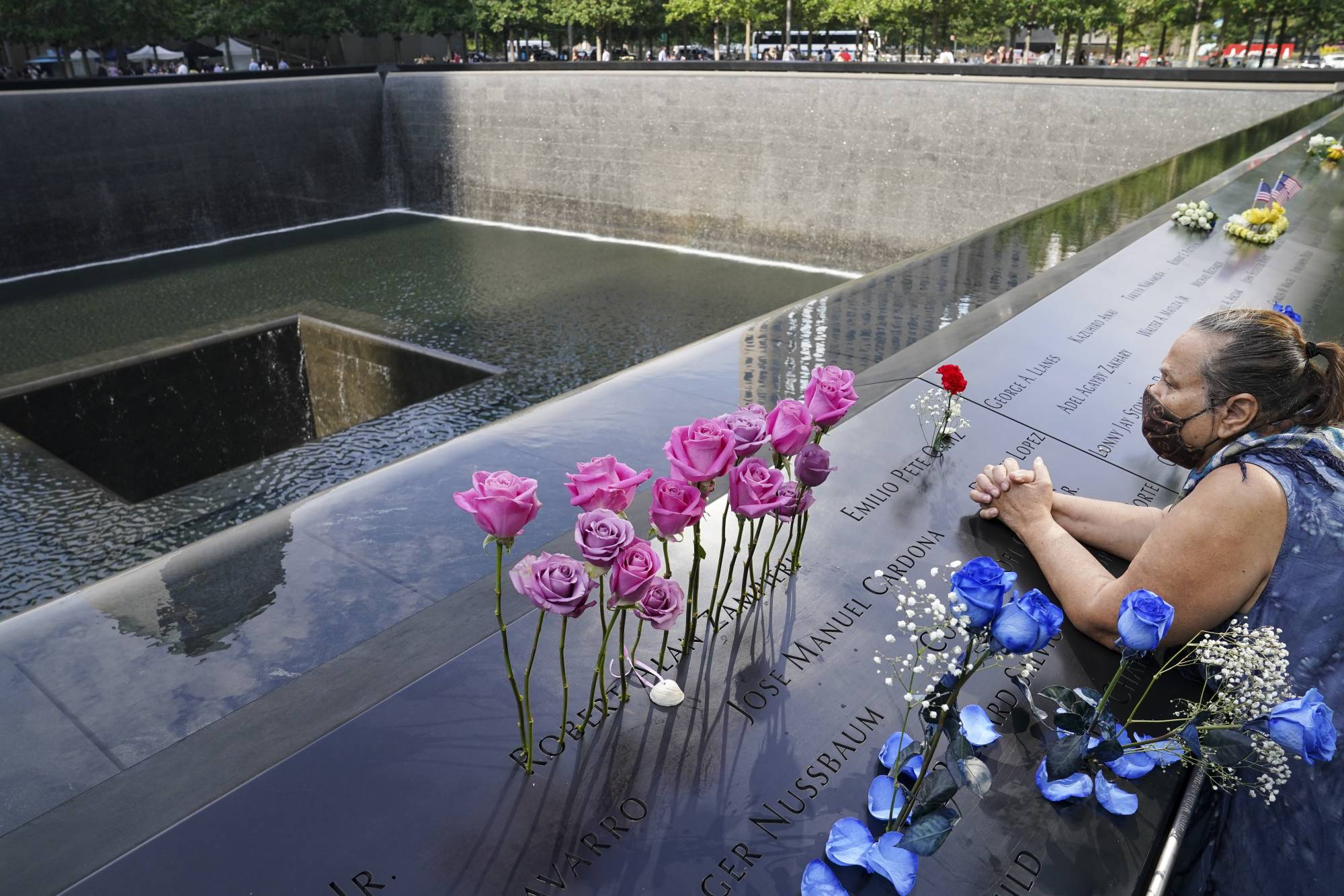 A mourner prays over the name cut-out of the deceased Emilio Pete Ortiz at the National September 11 Memorial and Museum, Friday, Sept. 11, 2020, in New York. Americans will commemorate 9/11 with tributes that have been altered by coronavirus precautions and woven into the presidential campaign. (AP Photo/John Minchillo)