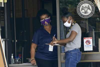 An employee of the Mississippi Department of Employment Security WIN Job Center in Pearl, Miss., left, assists a client fill out paperwork, Monday, Aug. 31, 2020. The Labor Department reported unemployment numbers Thursday, Sept. 3. (AP Photo/Rogelio V. Solis, File)