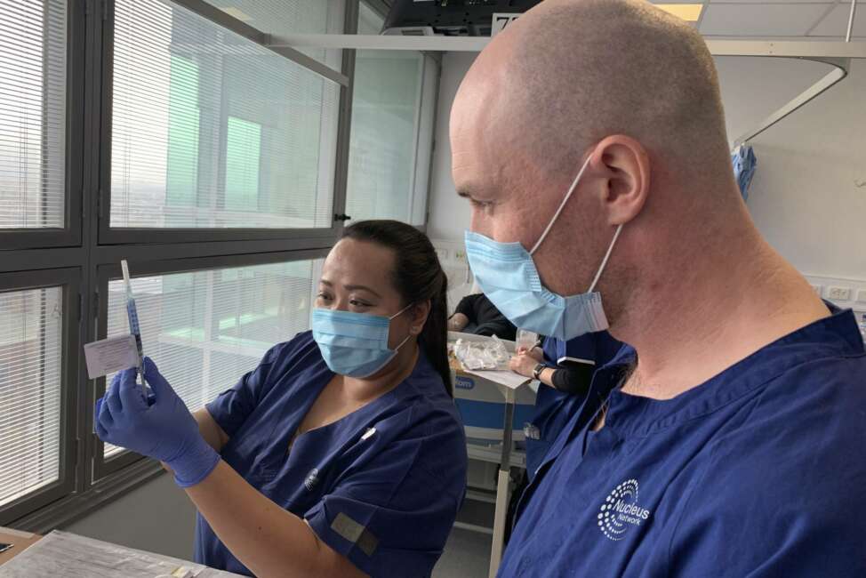 In this photo released by Nucleus Network/ABC, technicians prepare for a clinical trial of a coronavirus vaccine in Melbourne, Australia, Tuesday, May 26, 2020, with hopes of releasing a proven vaccine this year. Novavax will inject 131 volunteers in the first phase of the trial testing the safety of the vaccine and looking for signs of its effectiveness. (Patrick Rocca/Nucleus Network/ABC via AP)