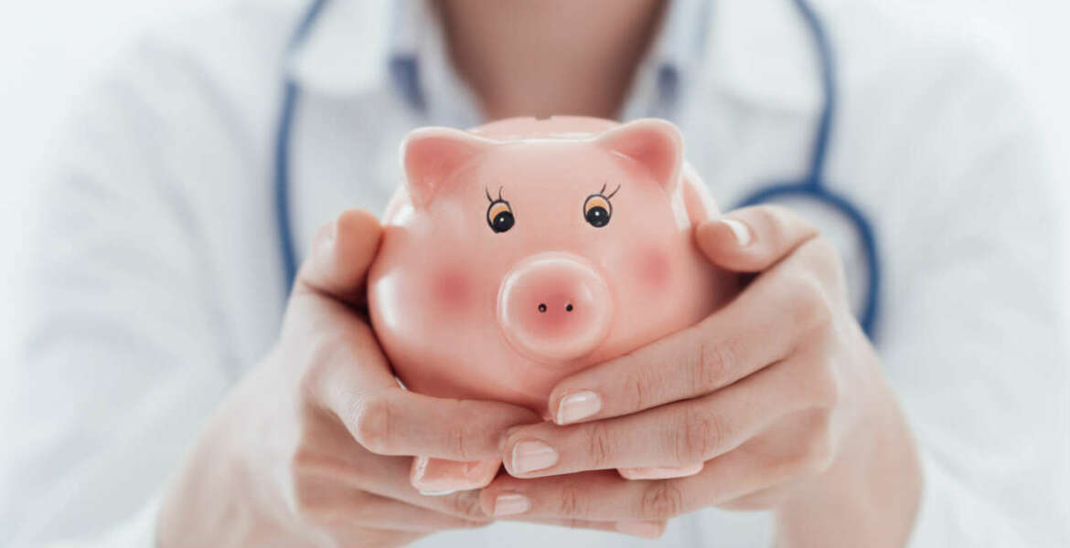 Female doctor holding a piggy bank: health insurance, medical expenses and tax concept