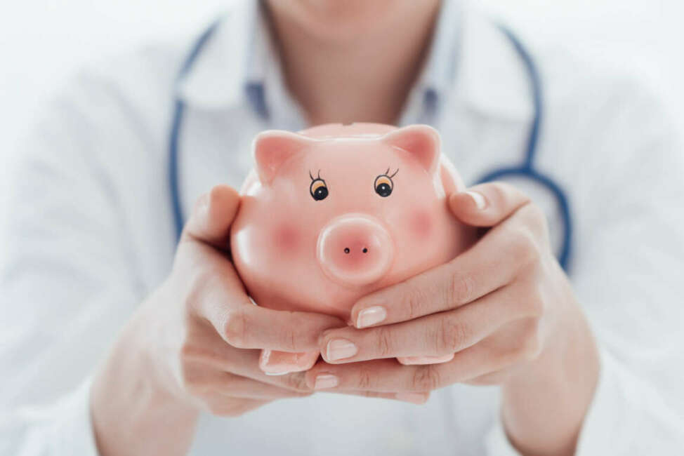 Female doctor holding a piggy bank: health insurance, medical expenses and tax concept