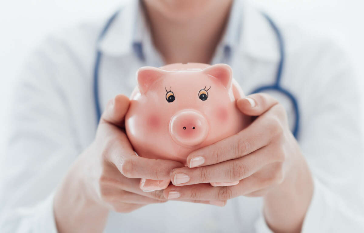 Female doctor holding a piggy bank: health insurance, medical expenses and tax concept