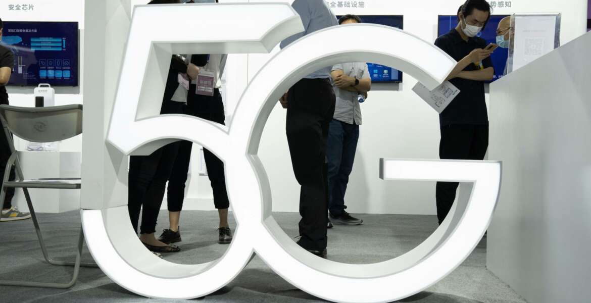 FILE - In this Sept. 17, 2020 file photo, visitors wearing mask to protect from the coronavirus walk past a 5G sign at the China Beijing International High Tech Expo in Beijing, China. A much-hyped network upgrade called “5G” means different things to different people. To industry proponents, it’s the next huge innovation in wireless internet. To the U.S. government, it’s the backbone technology of a future that America will wrestle with China to control.  (AP Photo/Ng Han Guan, File)