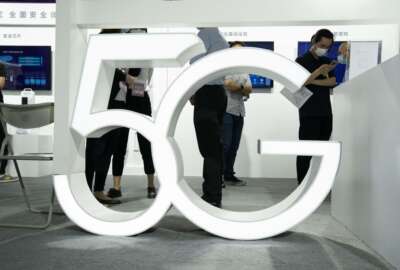 FILE - In this Sept. 17, 2020 file photo, visitors wearing mask to protect from the coronavirus walk past a 5G sign at the China Beijing International High Tech Expo in Beijing, China. A much-hyped network upgrade called “5G” means different things to different people. To industry proponents, it’s the next huge innovation in wireless internet. To the U.S. government, it’s the backbone technology of a future that America will wrestle with China to control.  (AP Photo/Ng Han Guan, File)