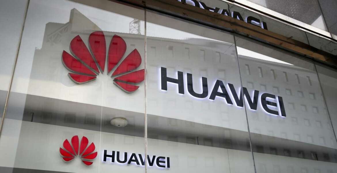 FILE - In this Jan. 29, 2019, file photo, logos of Huawei are displayed at its retail shop window with the reflection of the Ministry of Foreign Affairs office in Beijing. A committee of lawmakers on Thursday Oct. 8, 2020, is urging the British government to consider banning Chinese technology giant Huawei from the country's next-generation mobile phone networks two years earlier than planned. (AP Photo/Andy Wong, File)