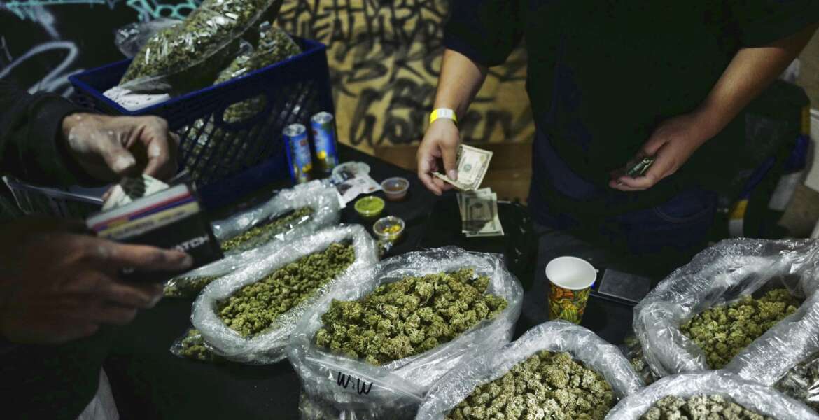 FILE - In this April 15, 2019, file photo, a vendor makes change for a marijuana customer at a cannabis marketplace in Los Angeles. Voters in four states could embrace broad legal marijuana sales on Election Day, setting the stage for a watershed year for the industry that could snowball into neighboring states as well as reshape policy on Capitol Hill. The Nov. 3, 2020, contests will take place in markedly different regions of the country, New Jersey, Arizona, South Dakota and Montana and approval of the proposals would highlight how public acceptance of cannabis is cutting across geography, demographics and the nation's deep political divide. (AP Photo/Richard Vogel, File)