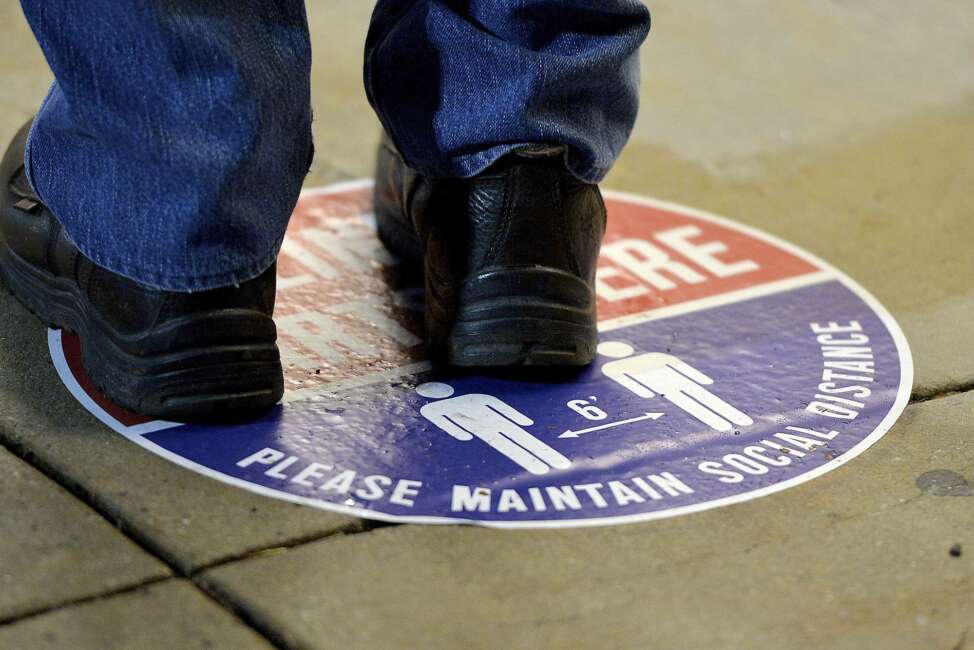 A voter stands on a social distance marker outside the Washington County Election Center in Hagerstown, Md., Monday, Oct. 26, 2020, for the first day of in-person early voting. (Colleen McGrath/The Herald-Mail via AP)