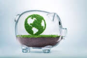 Grass growing in the shape of planet Earth, inside a transparent piggy bank, symbolising the need to invest in the protection of the environment and to reconnect with nature.