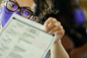 An election worker examines ballots as vote counting in the general election continues at State Farm Arena on Thursday, Nov. 5, 2020, in Atlanta. (AP Photo/Brynn Anderson)