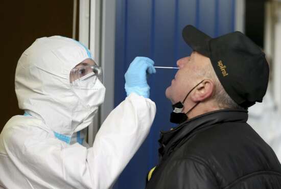 A medical worker, left, tests a man for COVID-19 in a set up for rapid new coronavirus testing in Vienna, Austria, Monday, Nov. 30, 2020. The Austrian government has moved to restrict freedom of movement for people, in an effort to slow the onset of the COVID-19 disease and the spread of the coronavirus. (AP Photo/Ronald Zak)
