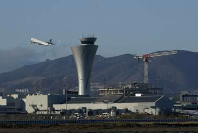 A plane takes off behind the air traffic control tower at San Francisco International Airport during the coronavirus outbreak in San Francisco, Tuesday, Nov. 24, 2020. (AP Photo/Jeff Chiu)