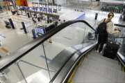 A traveler rides an escalator with her luggage as she arrives at the nearly empty JetBlue terminal at Logan Airport, Friday Nov. 20, 2020, in Boston. With the coronavirus surging out of control, the nation's top public health agency pleaded with Americans not to travel for Thanksgiving and not to spend the holiday with people from outside their household. (AP Photo/Michael Dwyer)