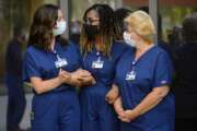 Shereyah Barbera, Annice Sterling, and Magdelena Litwinczuk, ICU nurses from Northwell Health, a New York hospital chain, who will support ICU teams at Intermountain Healthcare in Utah, link arms at a news conference in Murray, Utah on Tuesday, Aug. 4, 2020. (Trent Nelson/The Salt Lake Tribune via AP)