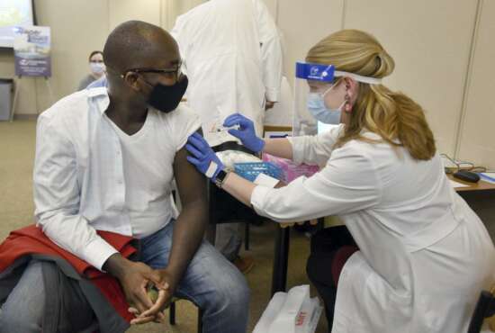 Dr. Cletus Oppong, who specializes in occupational medicine, is the first to receive the first round of the Moderna vaccine by Clinical Pharmacist Erin Conkright on Thursday morning , Dec. 24, 2020, at the Owensboro Health Regional Hospital in Owensboro, Ky. 