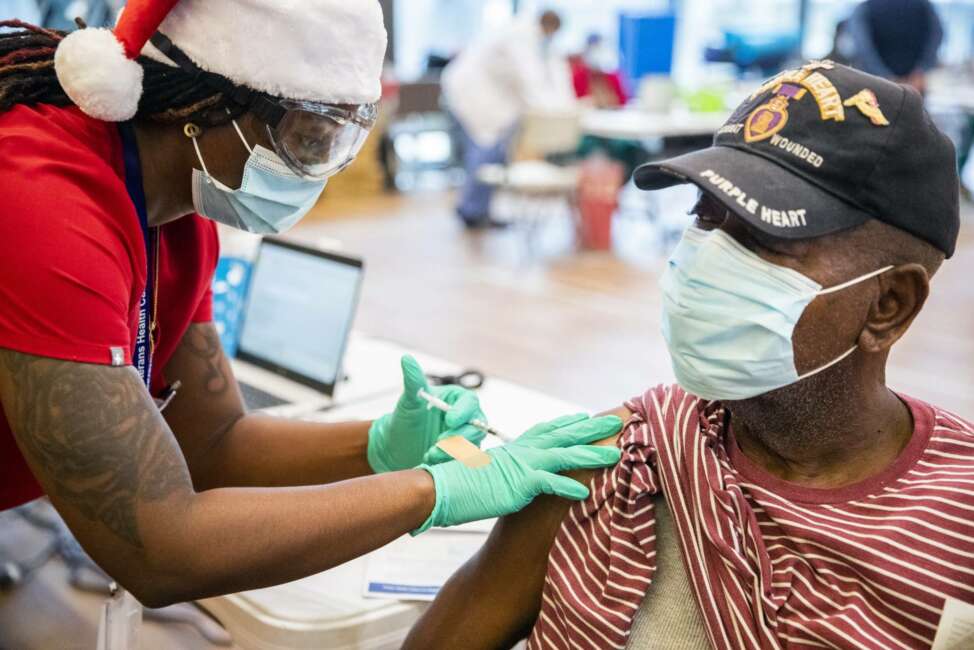 Vietnam veteran and Purple Heart recipient Alford Washington, Sr., receives a Pfizer-BioNTech COVID-19 vaccine from nurse Alanna Williams at the Southeast Louisiana Veterans Health Care System's gymnasium in New Orleans, Thursday, Dec. 24, 2020. Washington was part of the Pathfinder Unit in Vietnam where he survived a plane crash that killed 7 people in Oct. 28, 1967. He said he had no concerns receiving the COVID-19 vaccine. (Sophia Germer/The Times-Picayune/The New Orleans Advocate via AP)