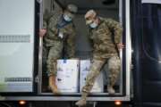 Romanian servicemen, wearing masks to protect against coronavirus, prepare to unload boxes containing the first batch of COVID-19 vaccines, at the National Center for Storage of the COVID-19 Vaccine, a military run facility, in Bucharest, Romania, Saturday, Dec. 26, 2020. Romanian authorities will start COVID-19 vaccinations on Sunday. (AP Photo/Vadim Ghirda)