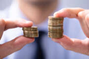 Man Holding Two Coin Stacks To Compare