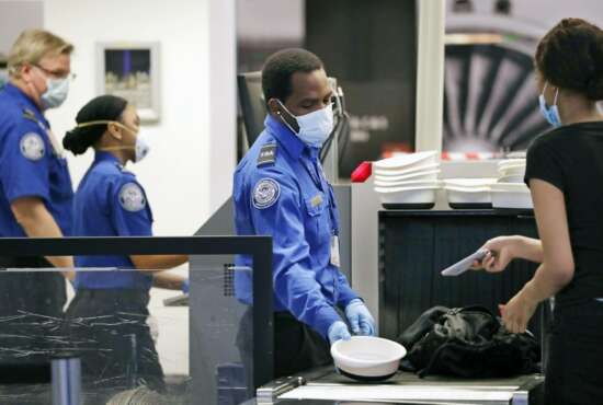 TSA officers wear protective masks at a security screening area at Seattle-Tacoma International Airport Monday, May 18, 2020, in SeaTac, Wash. Airlines say they are stepping up security on flights to Washington before next week’s inauguration of President-elect Joe Biden. Delta, United and Alaska airlines said Thursday, Jan. 14, 2021 they will bar passengers flying to Washington from putting guns in checked bags. (AP Photo/Elaine Thompson)
