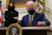 President Joe Biden signs executive orders on the economy in the State Dining Room of the White House, Friday, Jan. 22, 2021, in Washington. Vice President Kamala Harris looks on at left. (AP Photo/Evan Vucci)