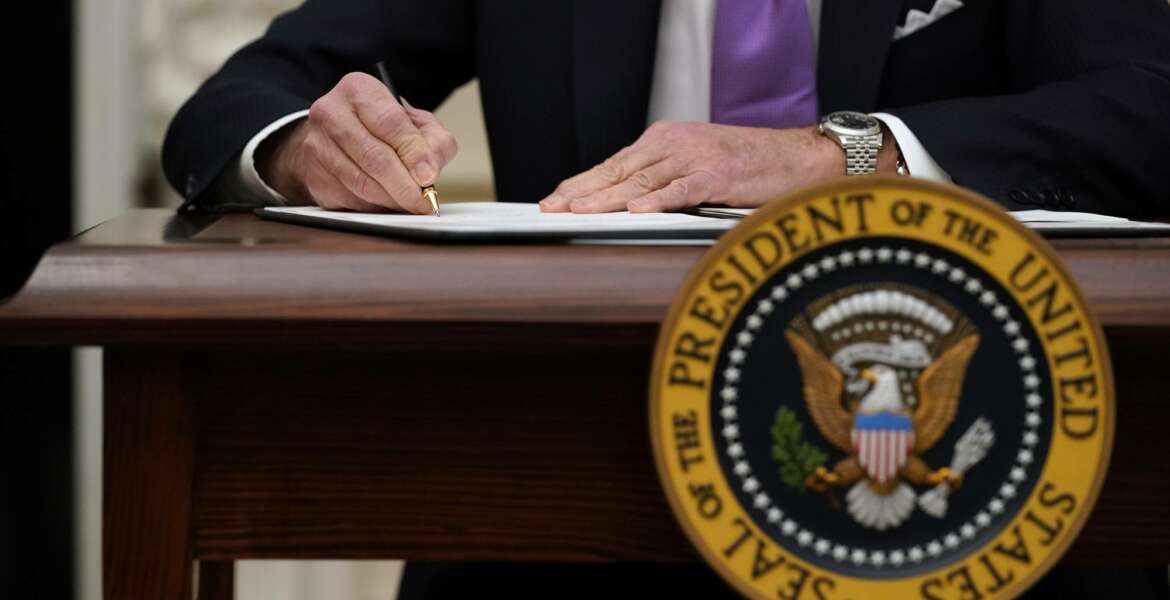 President Joe Biden signs executive orders after speaking about the coronavirus in the State Dinning Room of the White House, Thursday, Jan. 21, 2021, in Washington. (AP Photo/Alex Brandon)
