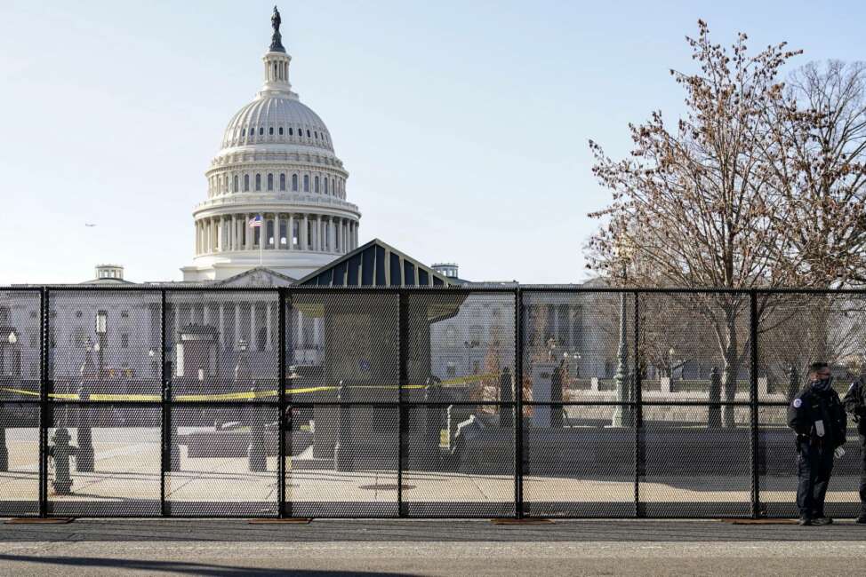 Capitol police officers stand outside of fencing that was installed around the exterior of the Capitol grounds, Thursday, Jan. 7, 2021 in Washington. The House and Senate certified the Democrat's electoral college win early Thursday after a violent throng of pro-Trump rioters spent hours Wednesday running rampant through the Capitol. A woman was fatally shot, windows were bashed and the mob forced shaken lawmakers and aides to flee the building, shielded by Capitol Police. (AP Photo/John Minchillo)