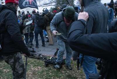 Demonstrators break TV equipment outside the the U.S. Capitol on Wednesday, Jan. 6, 2021, in Washington. (AP Photo/Jose Luis Magana)