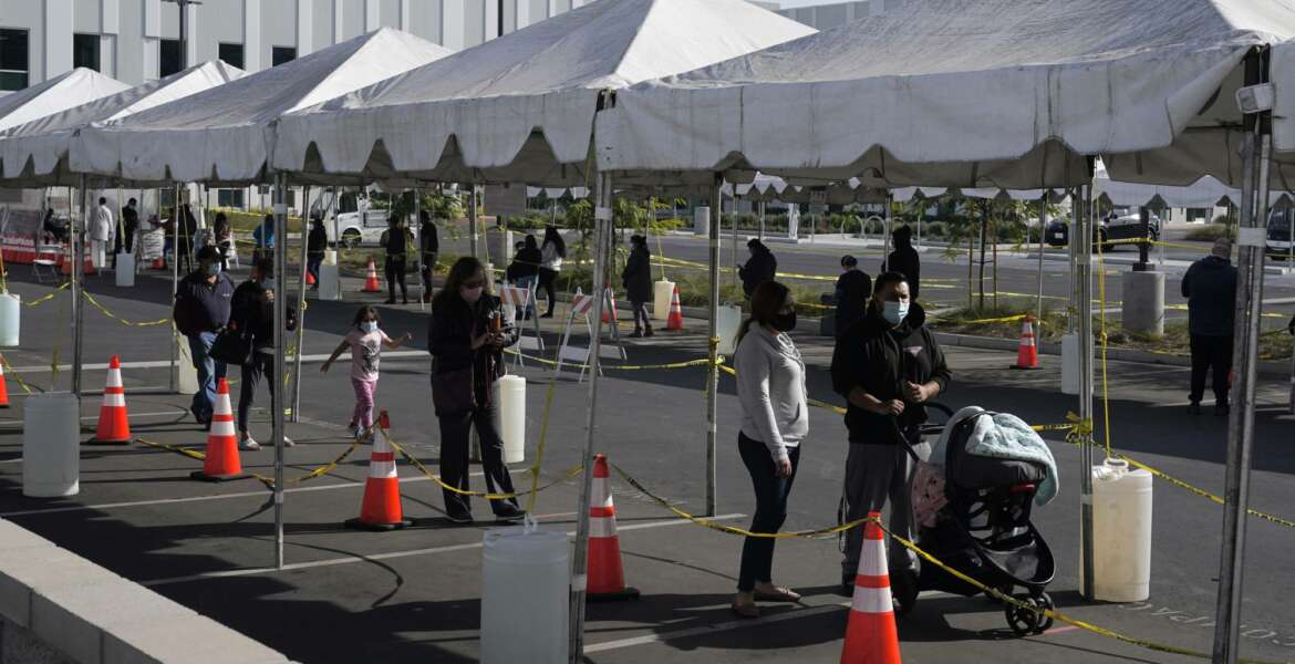 FILE - In this Jan. 7, 2021, file photo, people line up at a COVID-19 walk-up testing site on the Martin Luther King Jr. Medical Campus in Los Angeles. Coronavirus deaths and cases per day in the U.S. dropped markedly over the past couple of weeks but are still running at alarmingly high levels, and the effort to snuff out COVID-19 is becoming an ever more urgent race between the vaccine and the mutating virus. (AP Photo/Marcio Jose Sanchez, File)