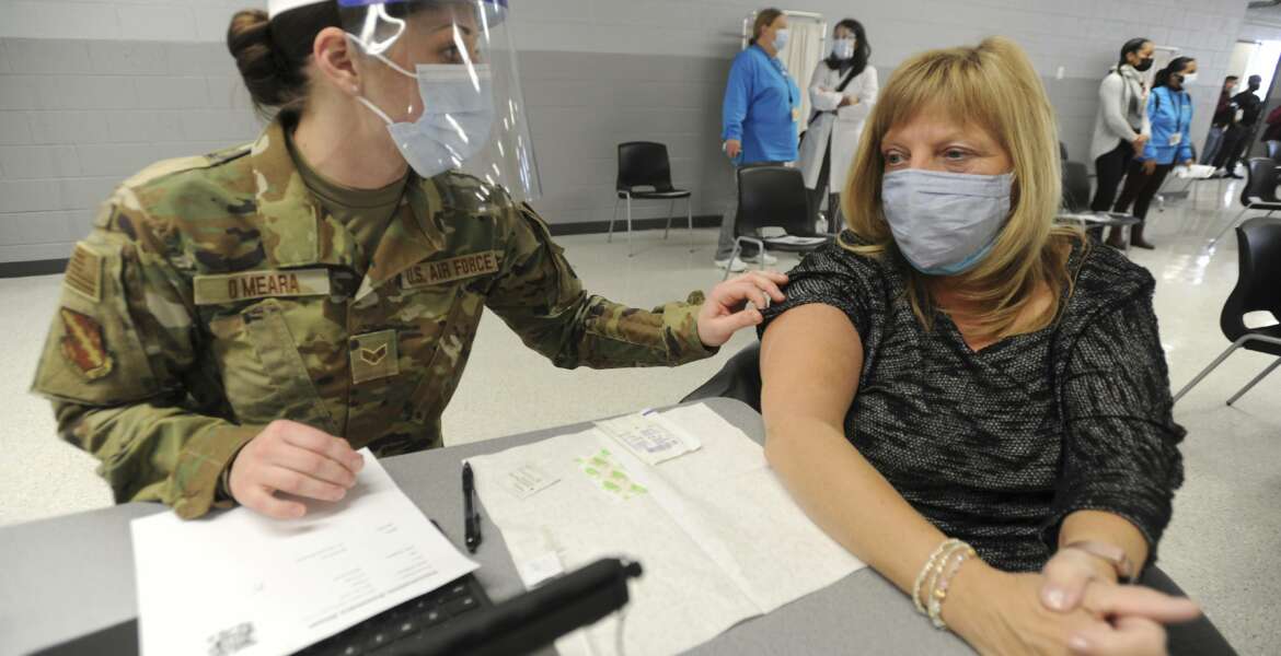 Lisa Meincke of Arlington Heights prepares herself to receive her first COVID-19 vaccination administered by National Guard personal Erika O'Meara of Scott Air Force base at Triton College, Wednesday, Feb. 3, 2021, in River Grove, Ill. This was opening day for the mass vaccinations sponsored by the Cook County Department of Public Health. (Mark Welsh/Daily Herald via AP)