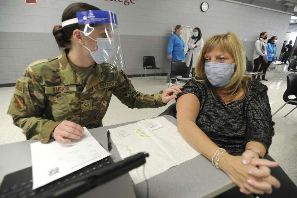 Lisa Meincke of Arlington Heights prepares herself to receive her first COVID-19 vaccination administered by National Guard personal Erika O'Meara of Scott Air Force base at Triton College, Wednesday, Feb. 3, 2021, in River Grove, Ill. This was opening day for the mass vaccinations sponsored by the Cook County Department of Public Health. (Mark Welsh/Daily Herald via AP)