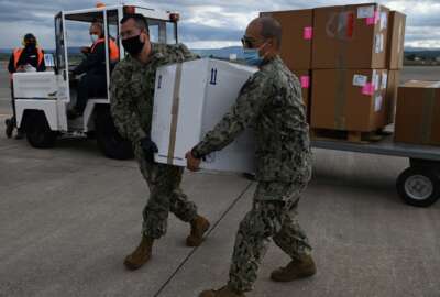 US Navy Sailors with Defense Logistics Agency Distribution Sigonella, prepare and load a box of COVID-19 vaccines to be shipped to the Nimitz-class aircraft carrier USS Dwight D. Eisenhower (CVN 69) from Naval Air Station Sigonella.