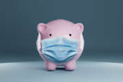 Piggy bank wearing a protective hygiene mask on blue background. Concept for saving, insurance, healthcare or financial economic crisis concept in time of coronavirus pandemic.