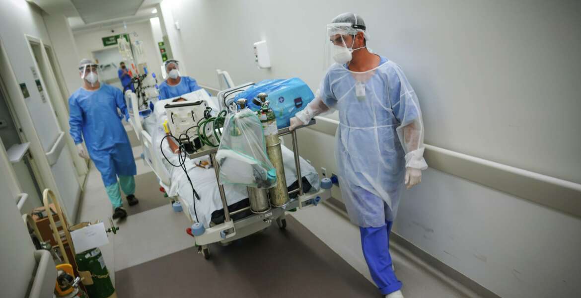 Healthcare workers transport a COVID-19 patient in an intensive care unit at the Hospital das Clinicas in Porto Alegre, Brazil, Friday, March 19, 2021. (AP Photo/Jefferson Bernardes)