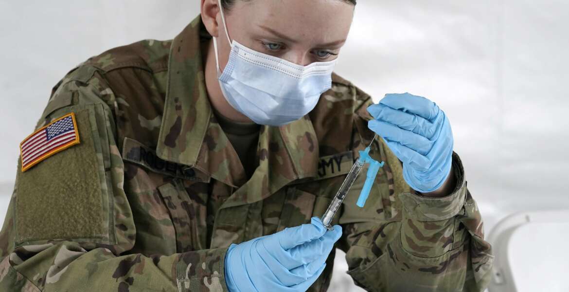 FILE - U.S. Army medic Kristen Rogers of Waxhaw, N.C. fills syringes with the Johnson & Johnson COVID-19 vaccine, Wednesday, March 3, 2021, in North Miami, Fla.  Critics in Florida say a doctor’s signature required for some people to get vaccinated is adding onerous barriers for some eligible residents, especially low-income or minority people who may not have health insurance or access to a primary care doctor.  (AP Photo/Marta Lavandier)