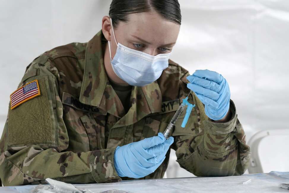 FILE - U.S. Army medic Kristen Rogers of Waxhaw, N.C. fills syringes with the Johnson &amp; Johnson COVID-19 vaccine, Wednesday, March 3, 2021, in North Miami, Fla.  Critics in Florida say a doctor’s signature required for some people to get vaccinated is adding onerous barriers for some eligible residents, especially low-income or minority people who may not have health insurance or access to a primary care doctor.  (AP Photo/Marta Lavandier)