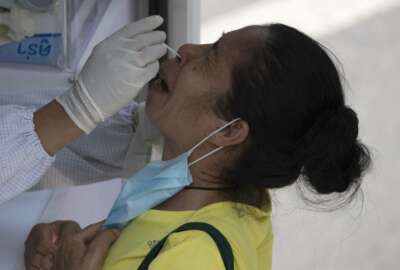 A health worker collects a nasal swab from a woman for a coronavirus test in Bangkok, Thailand, Monday, March 15, 2021. Thai authorities set up mobile testing units for COVID-19 near a market where a new cluster of over a hundred cases was confirmed over the weekend. (AP Photo/Sakchai Lalit)