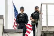 U.S. Secret Service police officers stand guard on the roof in front of the the American flag as it files at half-staff above the White House in Washington, Friday, April 16, 2021. (AP Photo/Andrew Harnik)