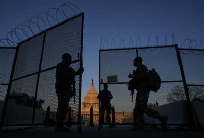 FILE - In this March 8, 2021, file photo, members of the National Guard open a gate in the razor wire topped perimeter fence around the Capitol at sunrise in Washington. Threats to members of Congress have more than doubled this year, according to the U.S. Capitol Police, and many members say they fear for their personal safety more than they did before the siege. (AP Photo/Carolyn Kaster, File)