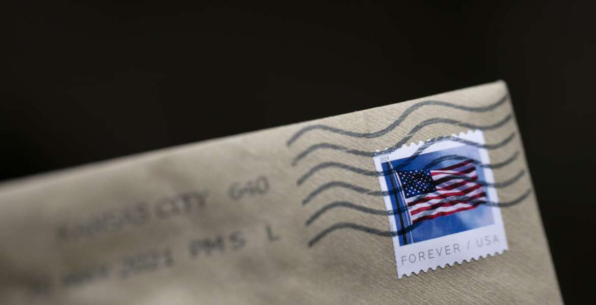 A stamp is shown on an envelope Friday, May 28, 2021, in Washington. The U.S. Postal Service is raising rates on first class stamps from 55 cents to 58 as part of a host of price hikes and service changes designed to reduce debt for the beleaguered agency. The changes, which will take effect on Aug. 29, include price hikes for first class mail, magazines and marketing mailers. (AP Photo/Jenny Kane)