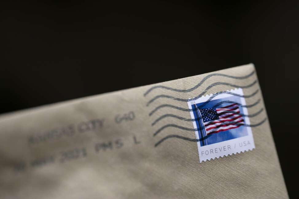 A stamp is shown on an envelope Friday, May 28, 2021, in Washington. The U.S. Postal Service is raising rates on first class stamps from 55 cents to 58 as part of a host of price hikes and service changes designed to reduce debt for the beleaguered agency. The changes, which will take effect on Aug. 29, include price hikes for first class mail, magazines and marketing mailers. (AP Photo/Jenny Kane)