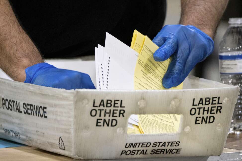 FILE - In this Jan. 5, 2021 file photo, Fulton County Georgia elections workers process absentee ballots for the Senate runoff election in Atlanta.  When voters in Florida and Georgia request mailed ballots next year, they will have to make sure they do one more thing before sending it in: provide proof of identification.  (AP Photo/Ben Gray, File)